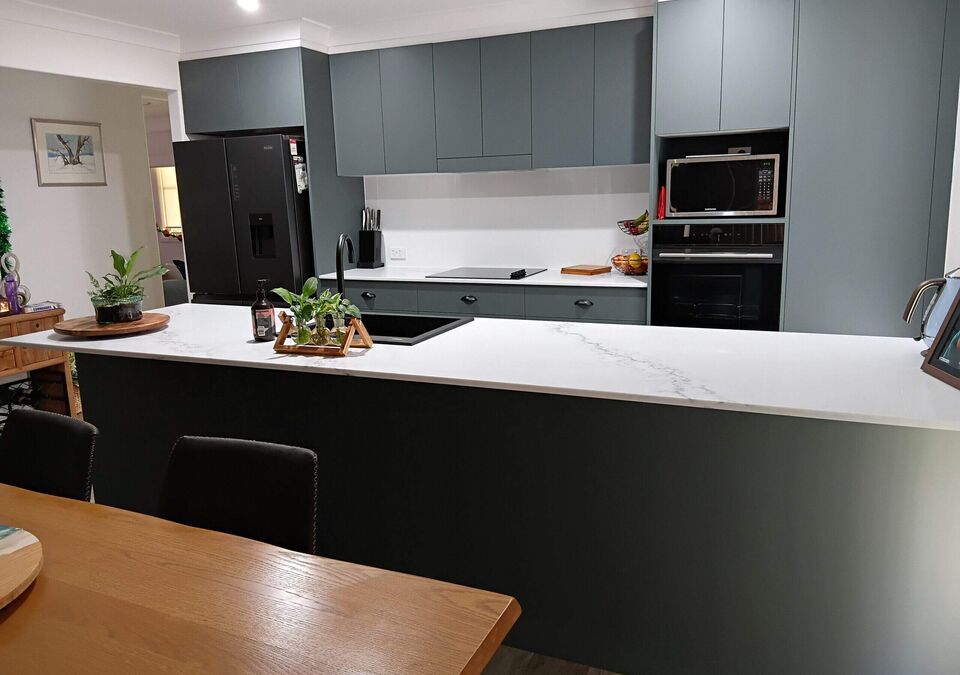 A grey and white kitchen with a stone island