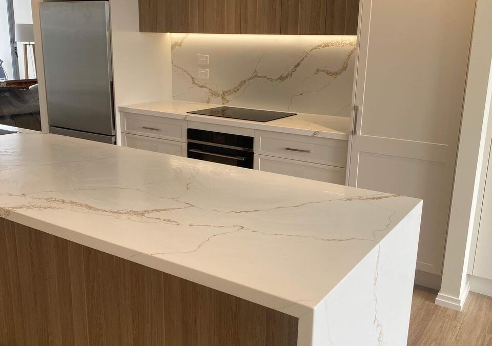 A white stone island with timber kitchen cabinetry
