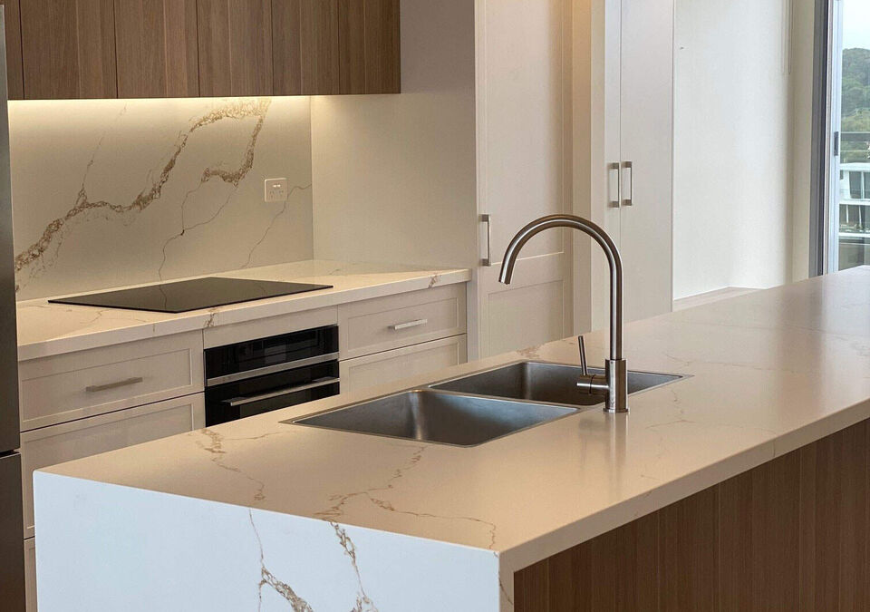 A white stone kitchen island with timber cabinetry