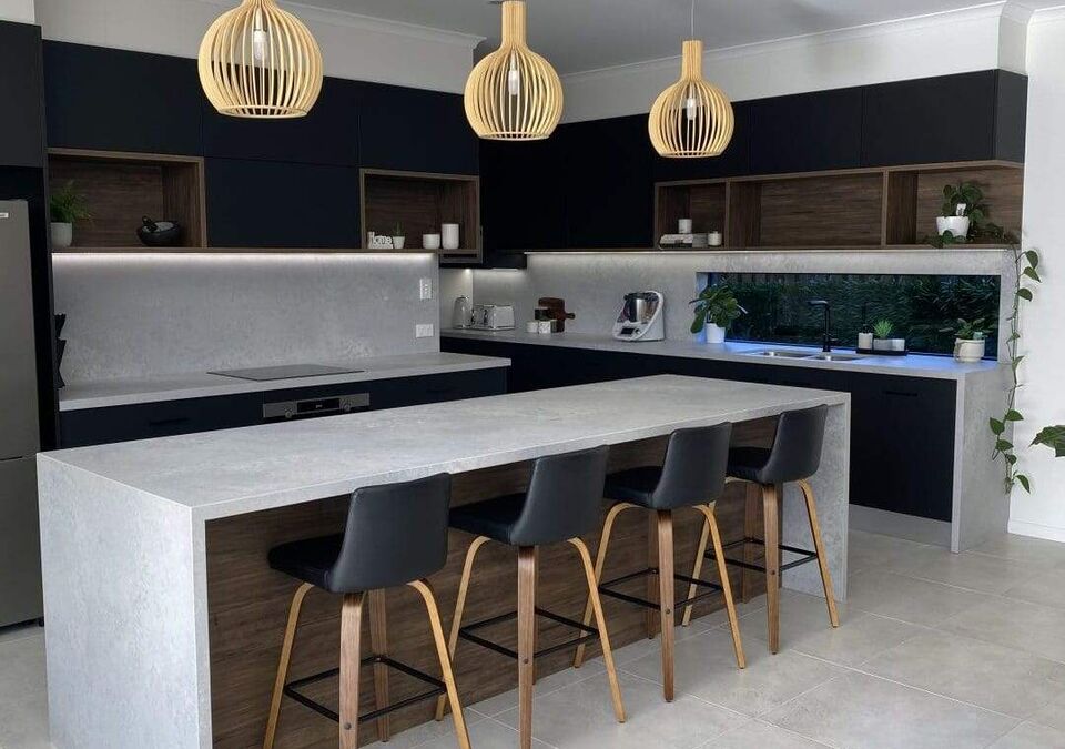A dark kitchen with a white stone island