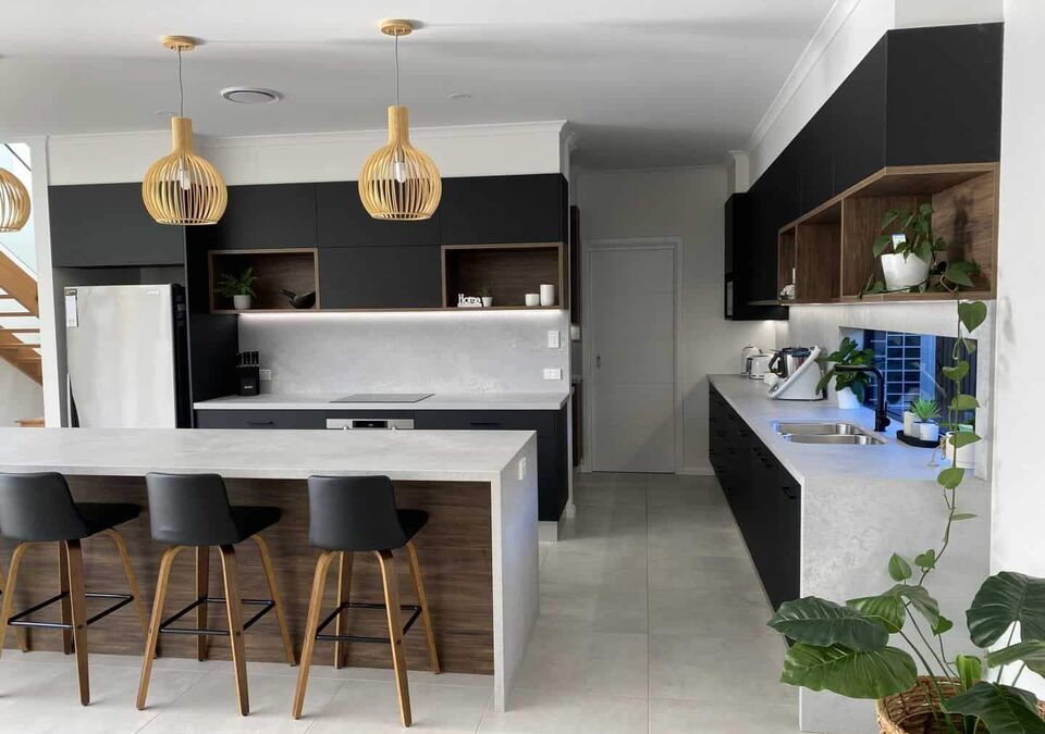 A kitchen with a white island and pendant lights
