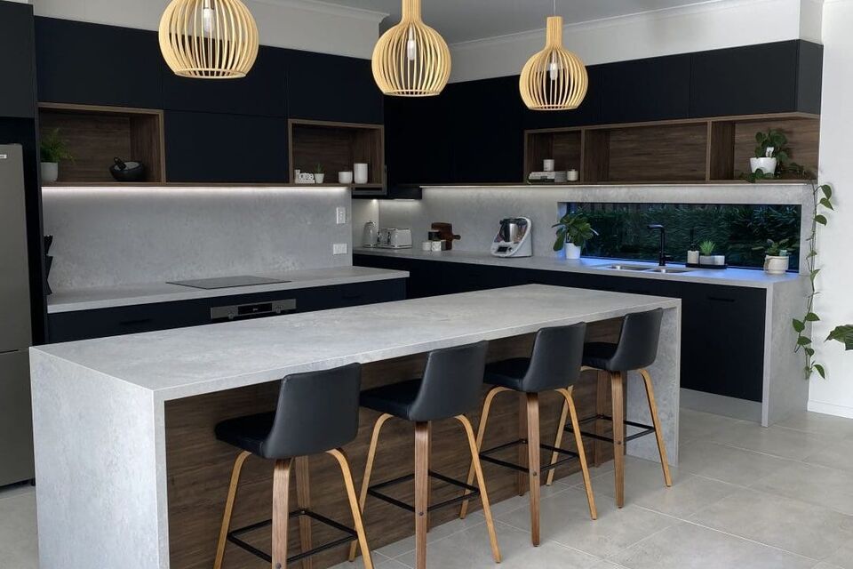 A dark kitchen with a white stone island